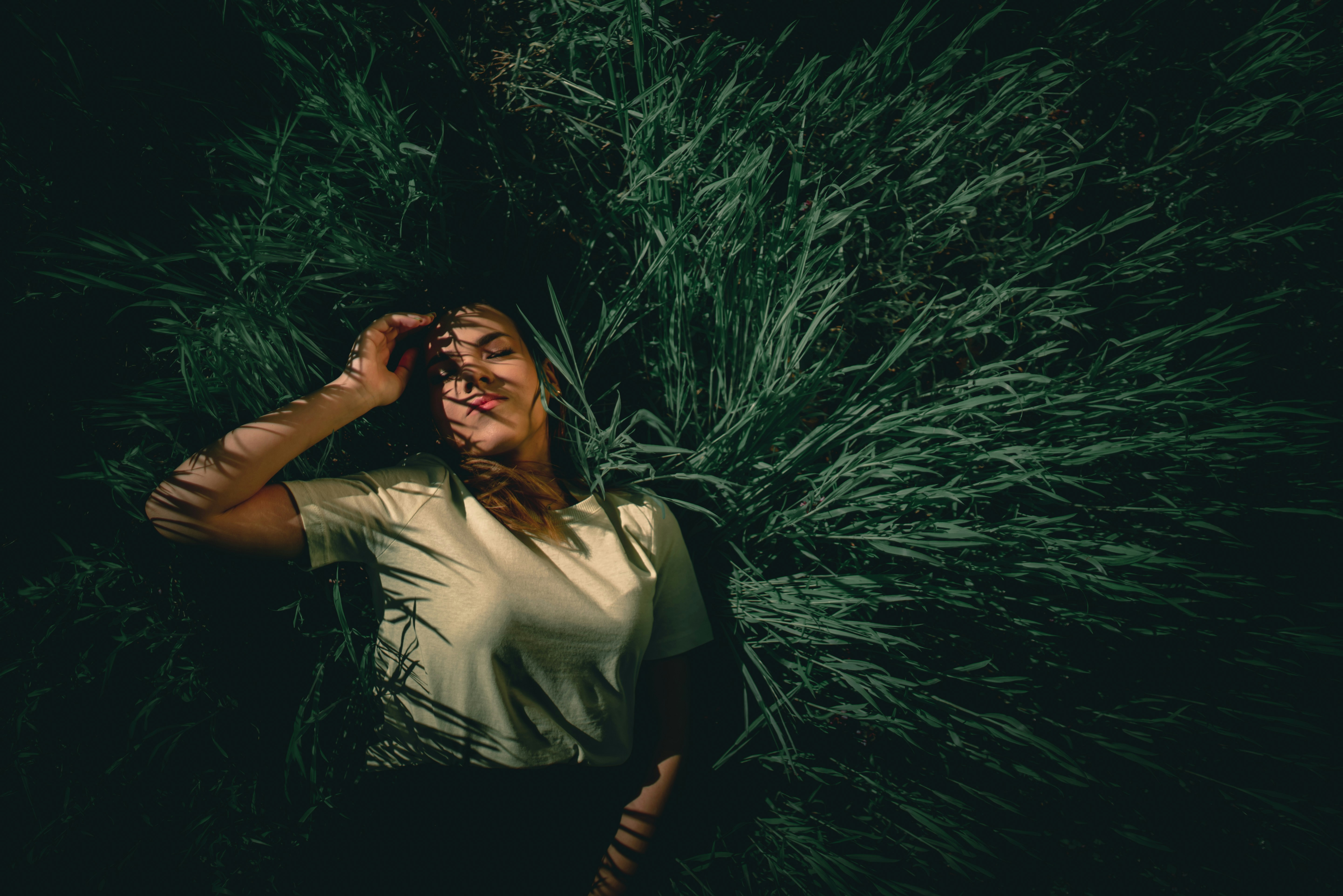 woman in white shirt standing beside green grass