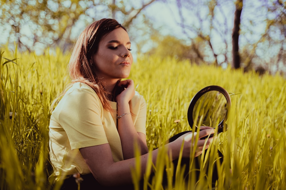woman in white shirt sitting on grass field during daytime