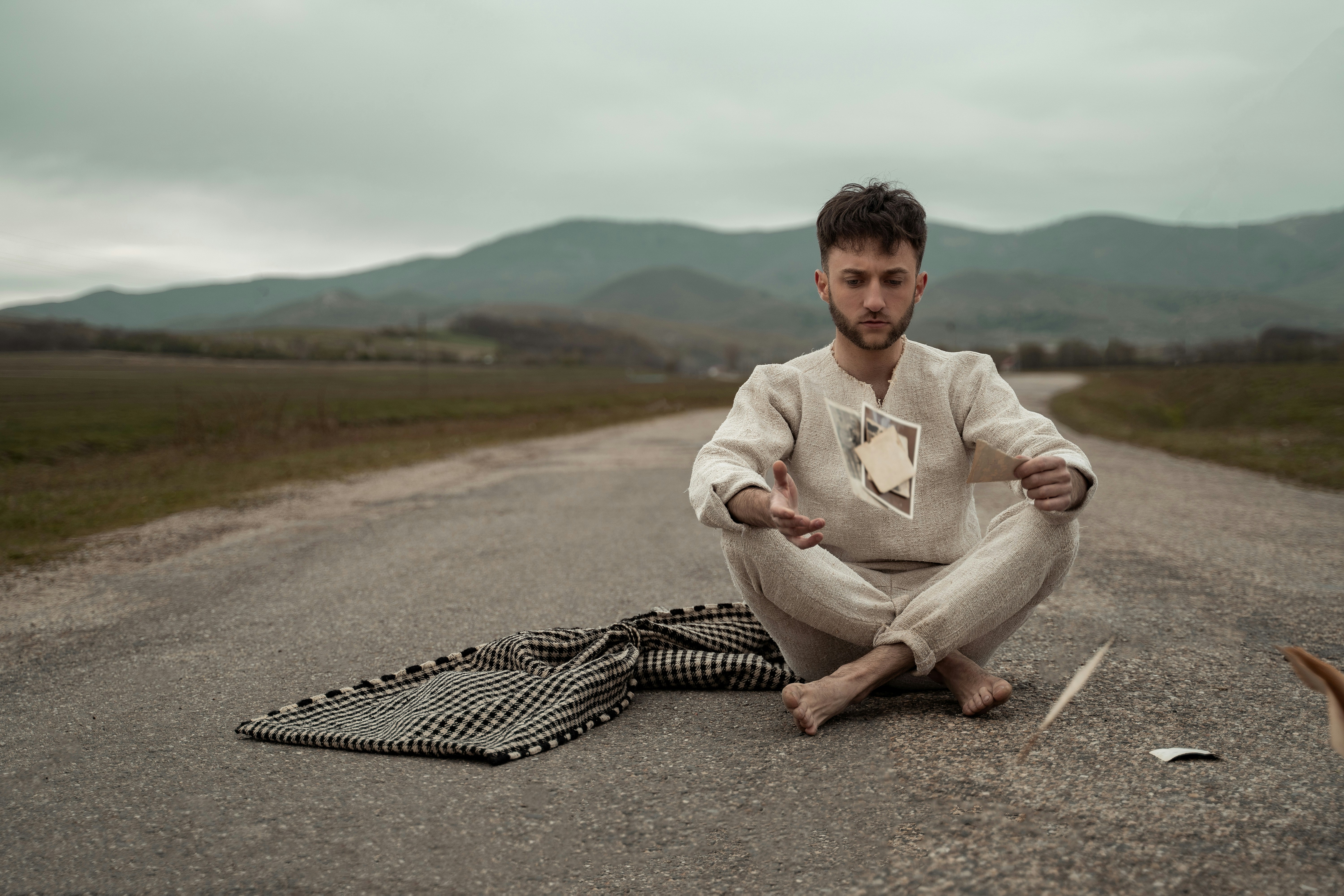 man in white hoodie sitting on gray concrete road during daytime