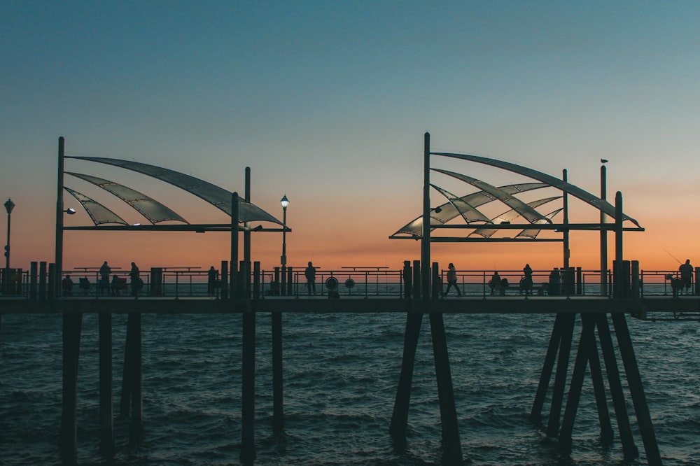 silhouette of people on bridge during sunset