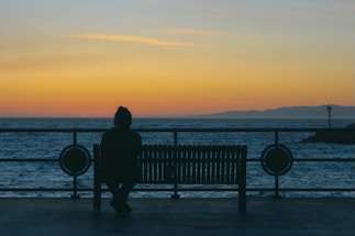 silhouette of person standing on dock during sunset