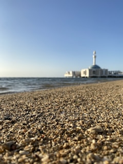 A scenic view of a quiet beach in Malaysia with prayer mats laid out near the shore.