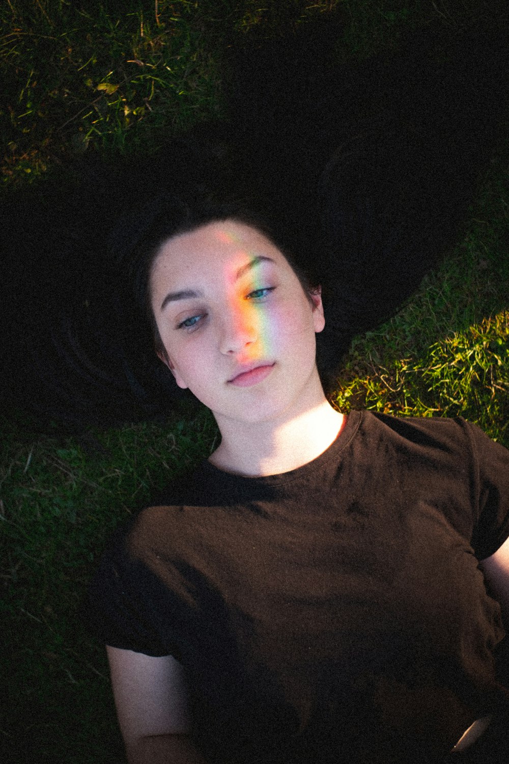 woman in black crew neck shirt lying on green grass