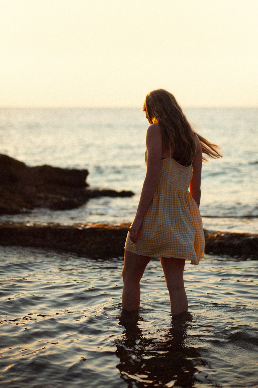 woman in pink dress standing on seashore during daytime