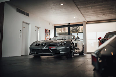 A sleek silver Mercedes-Benz parked in a softly lit minimalist showroom with pastel blue accents.