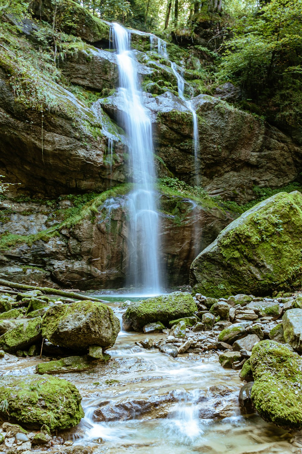 water falls on rocky shore during daytime