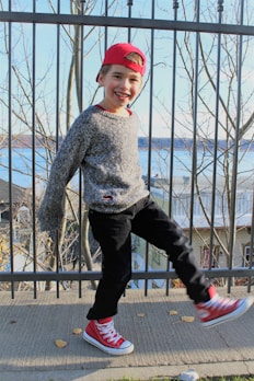 A child wearing a cozy gray sweater and playful sneakers, running through a park in autumn.