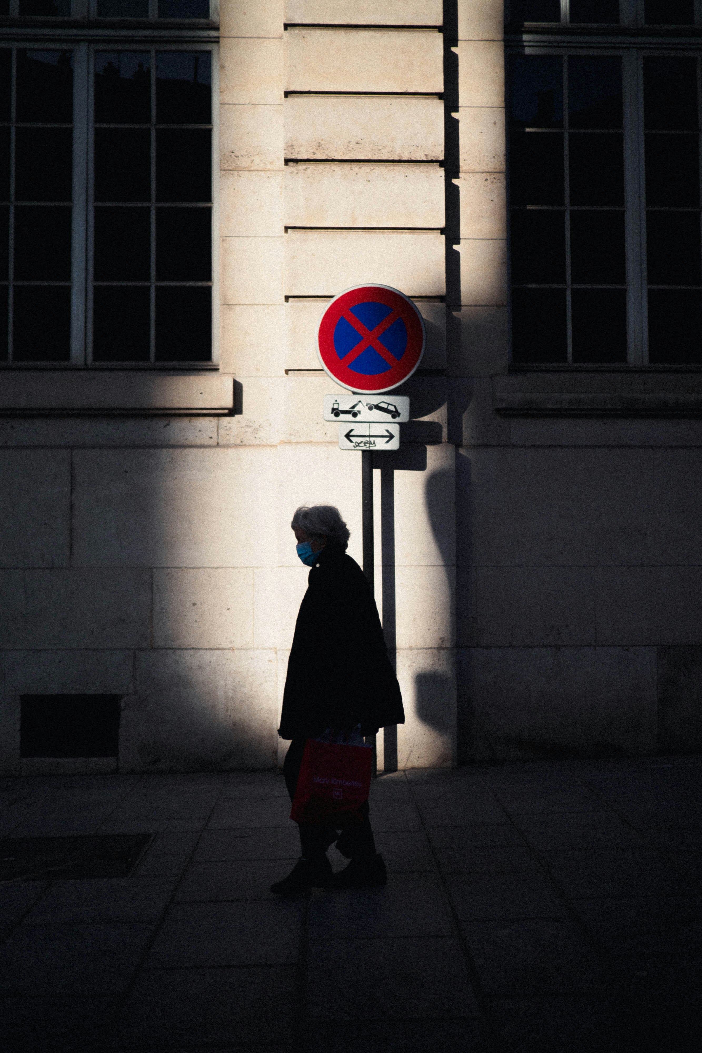 man in black coat standing near red and white stop sign