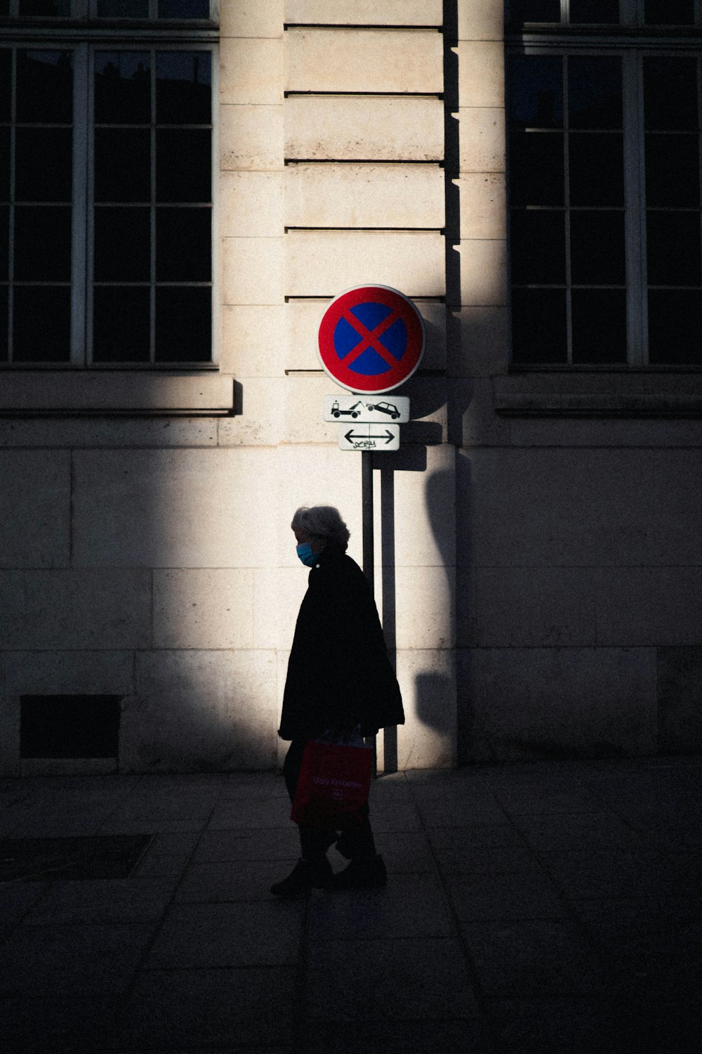 man in black coat standing near red and white stop sign