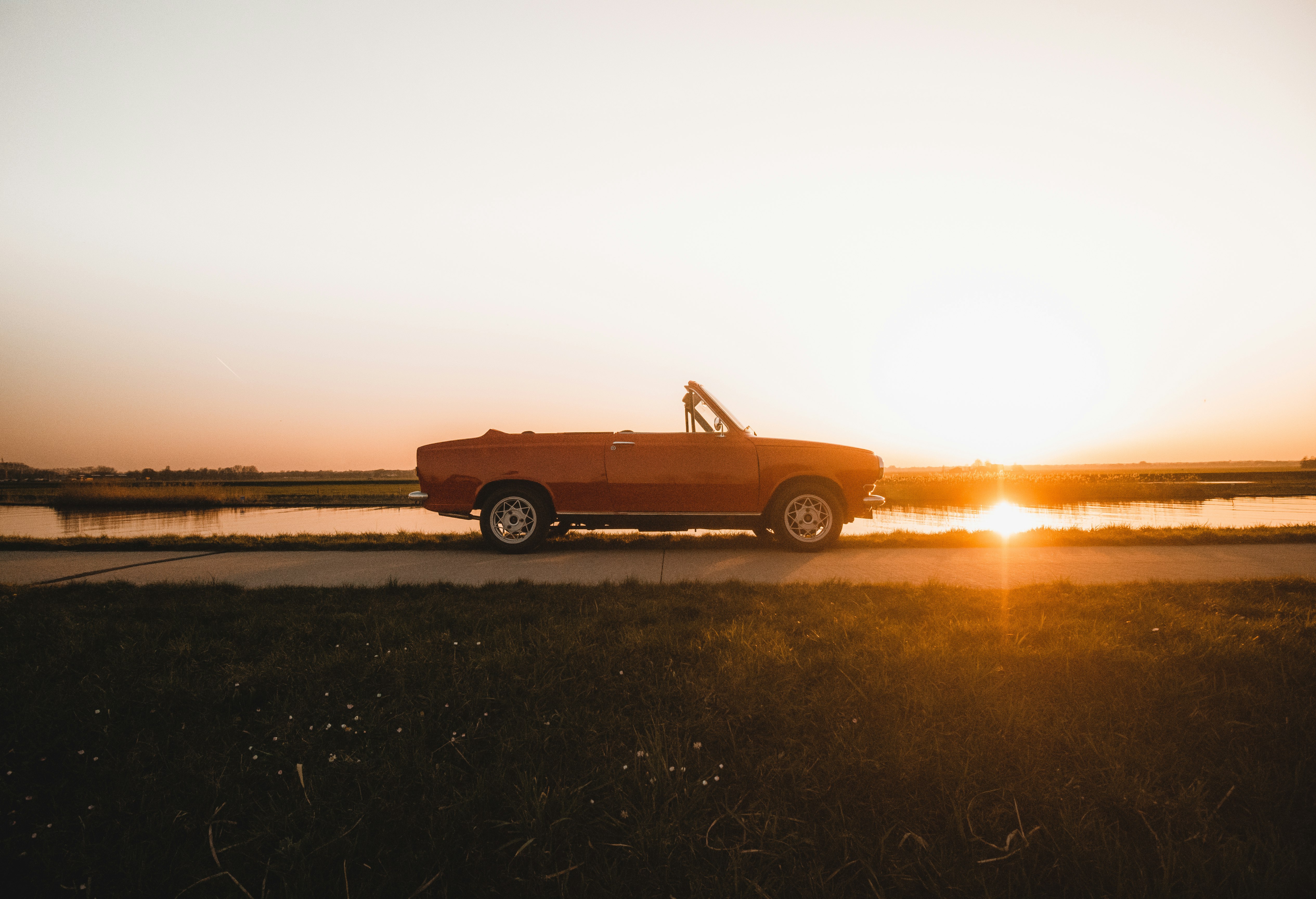orange car on brown field during sunset