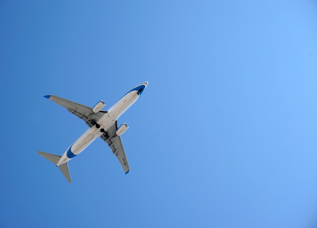 white airplane in mid air during daytime