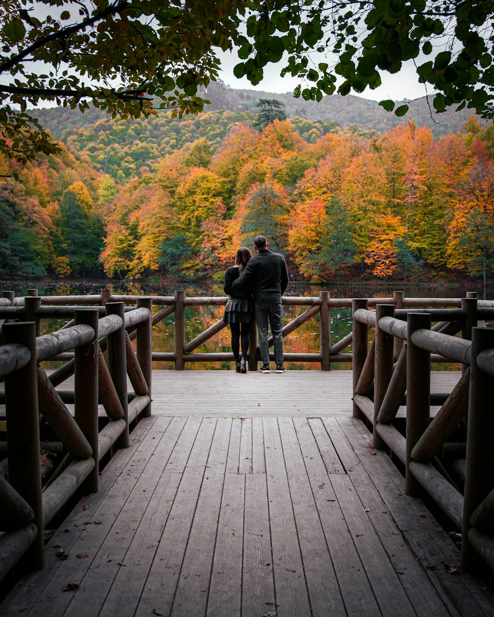 man in black jacket walking on wooden bridge