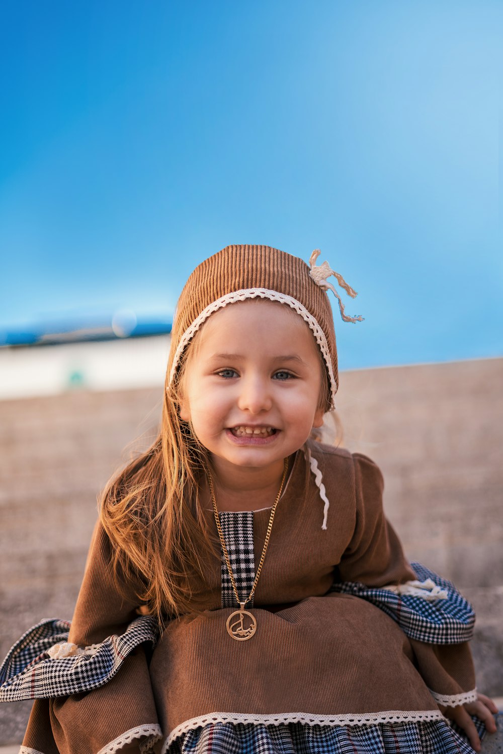 girl in brown jacket and blue and white plaid scarf