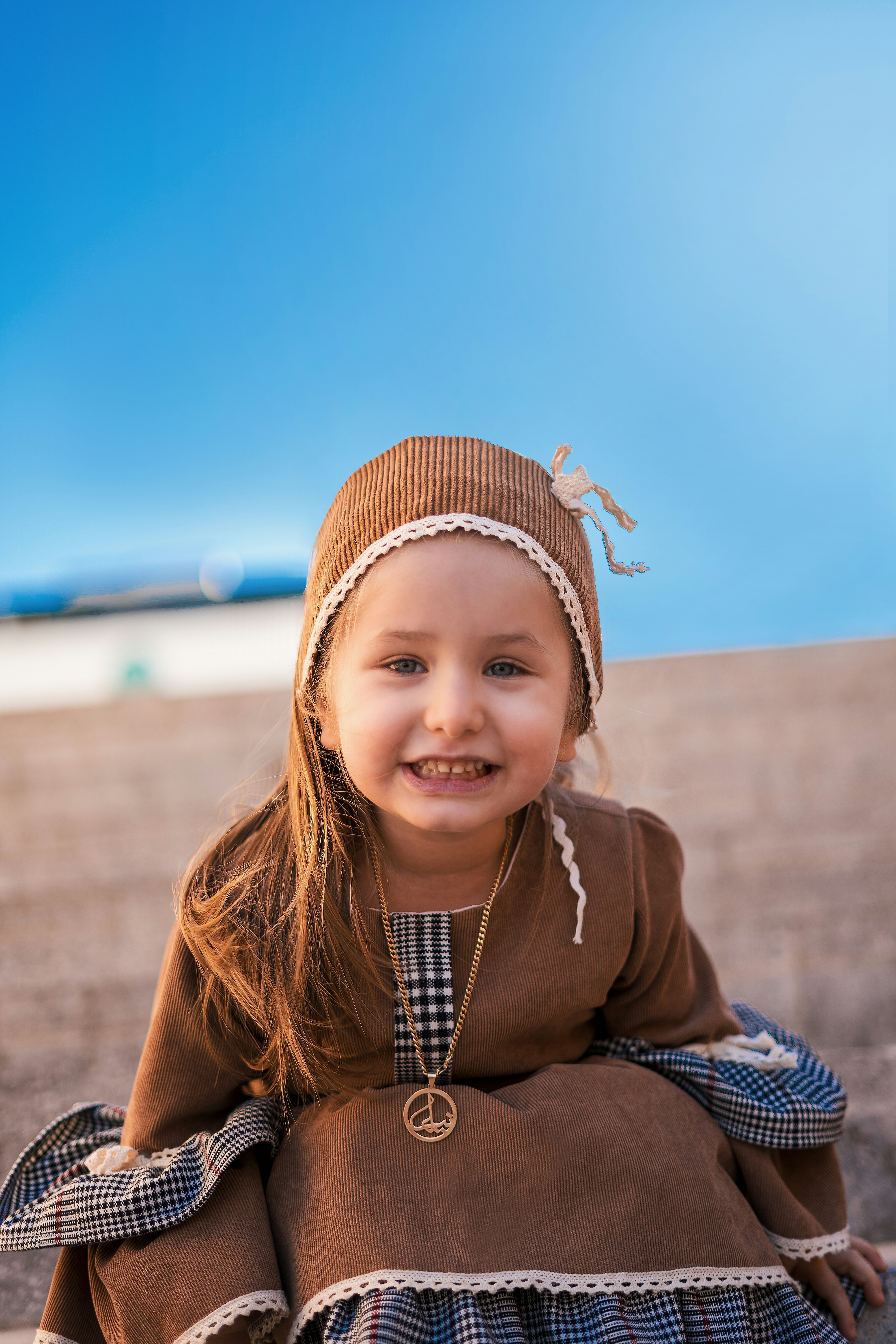 girl in brown jacket and blue and white plaid scarf