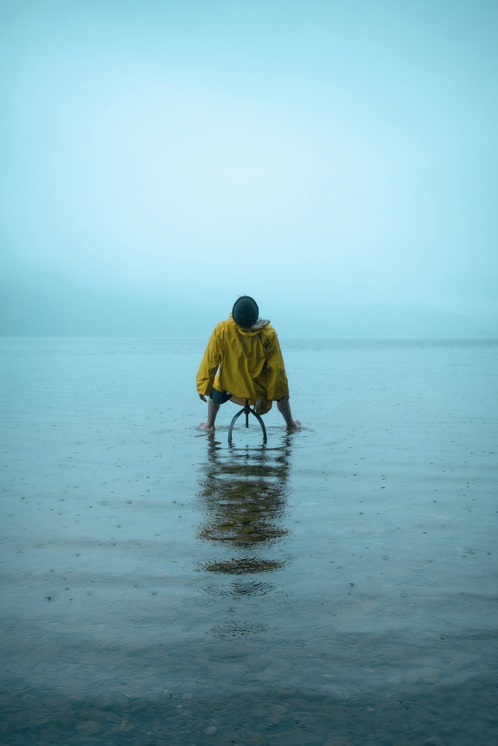 homem no capuz amarelo andando na praia durante o dia