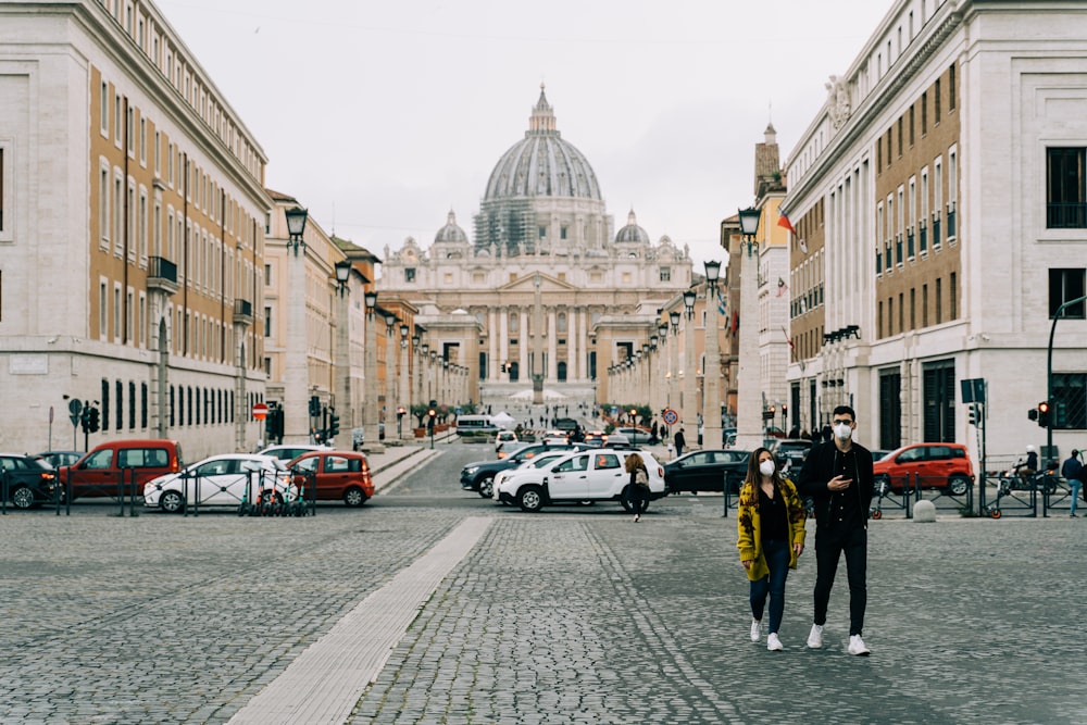 people walking on sidewalk near cars and buildings during daytime