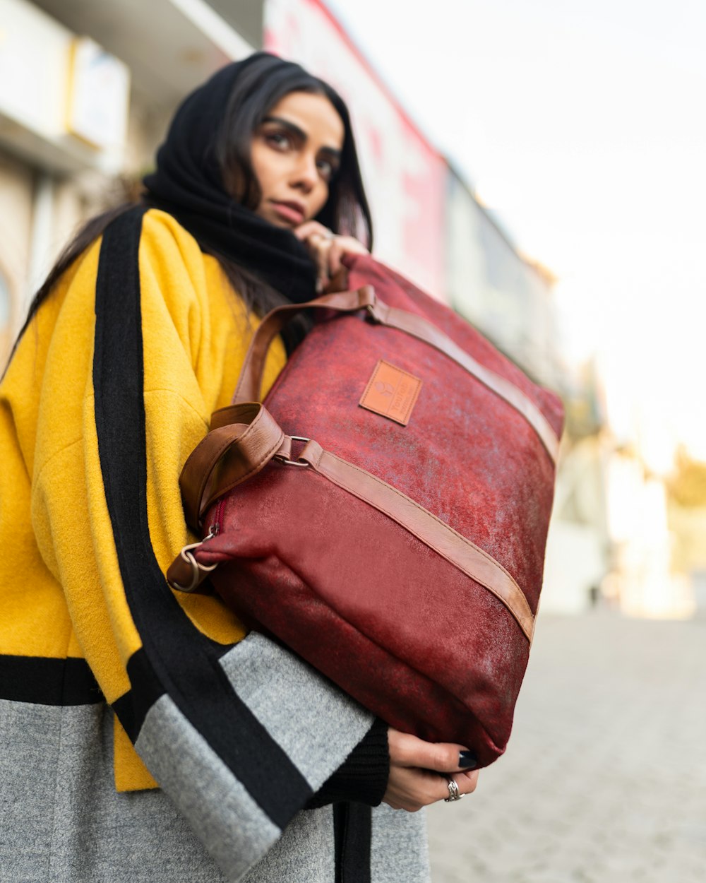 woman in yellow and black coat carrying red leather handbag
