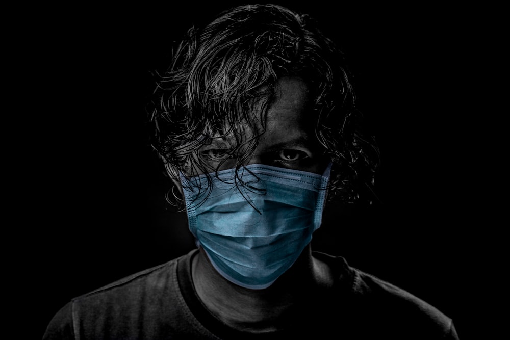 Homme en chemise à col rond noir avec masque facial bleu