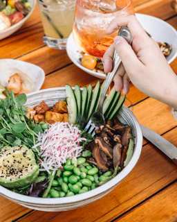 Gentle hands holding a bowl of colorful salad with nuts and seeds, symbolizing mindful eating