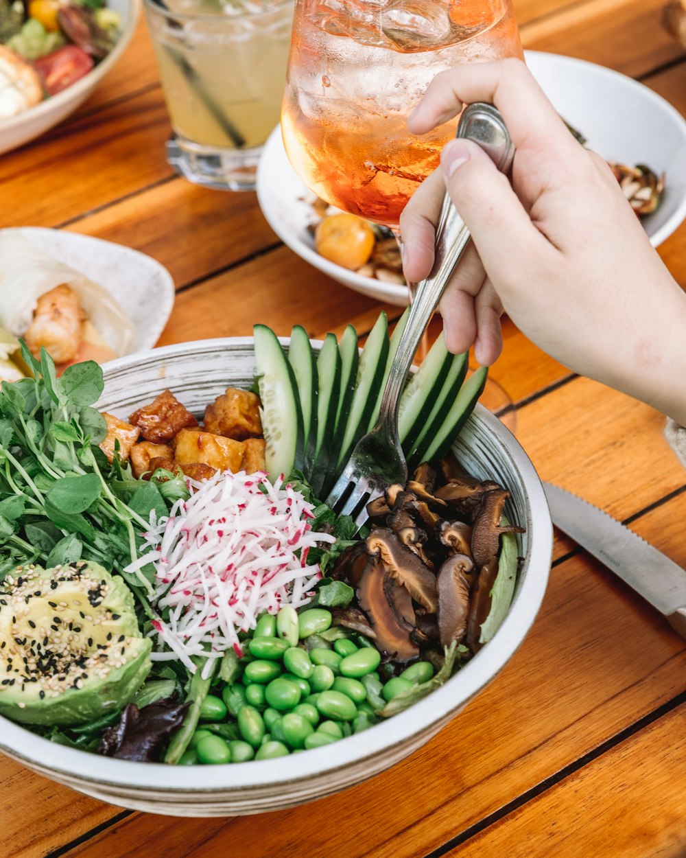 person holding stainless steel fork and knife slicing vegetable on white ceramic plate