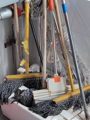 A variety of cleaning equipment including mops, brushes, and safety gloves.