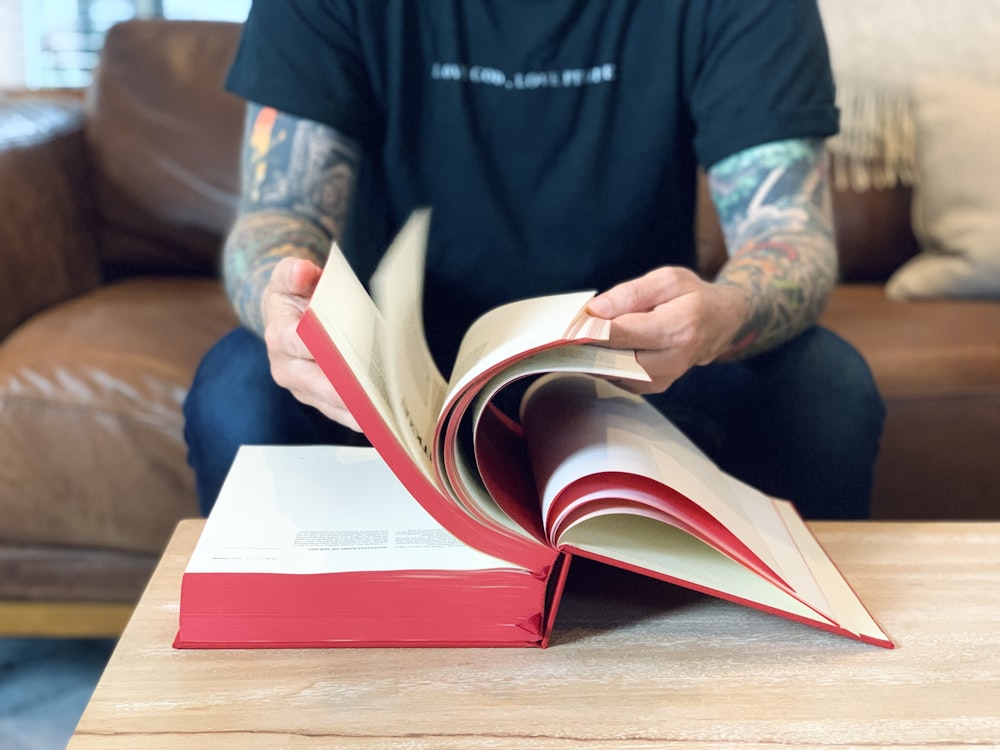 person in blue and white adidas shirt holding red book