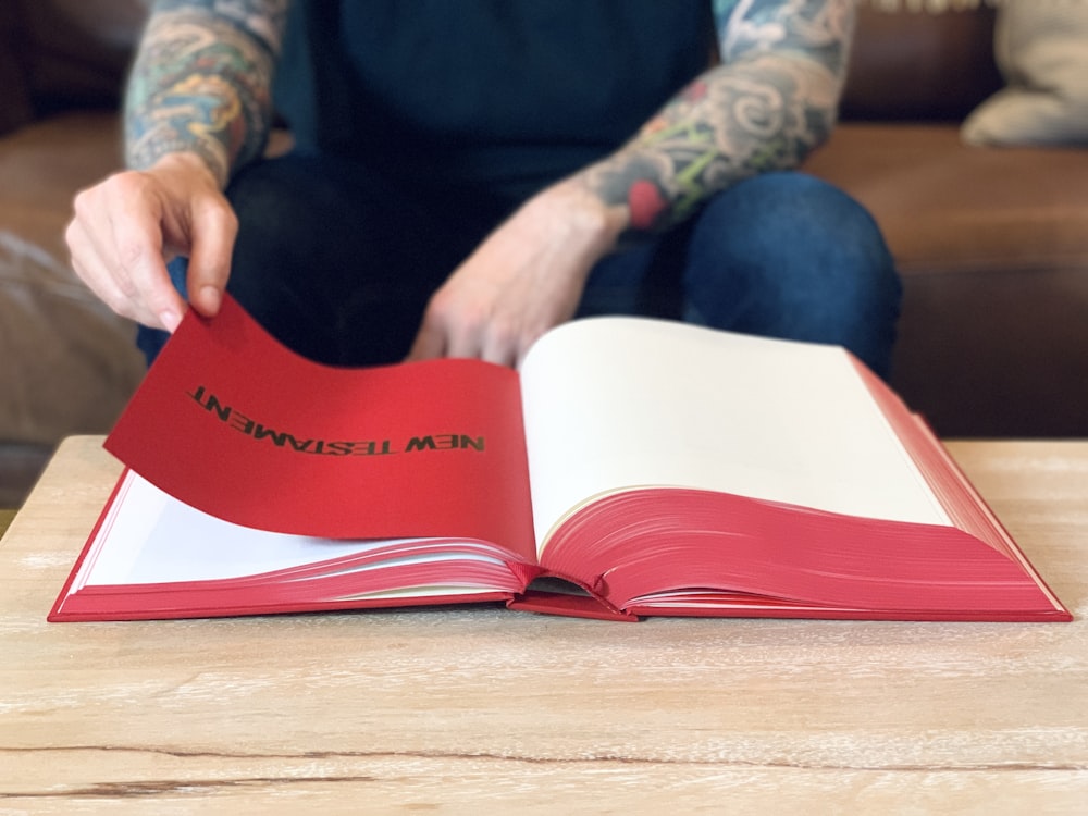 person holding red paper on brown wooden table