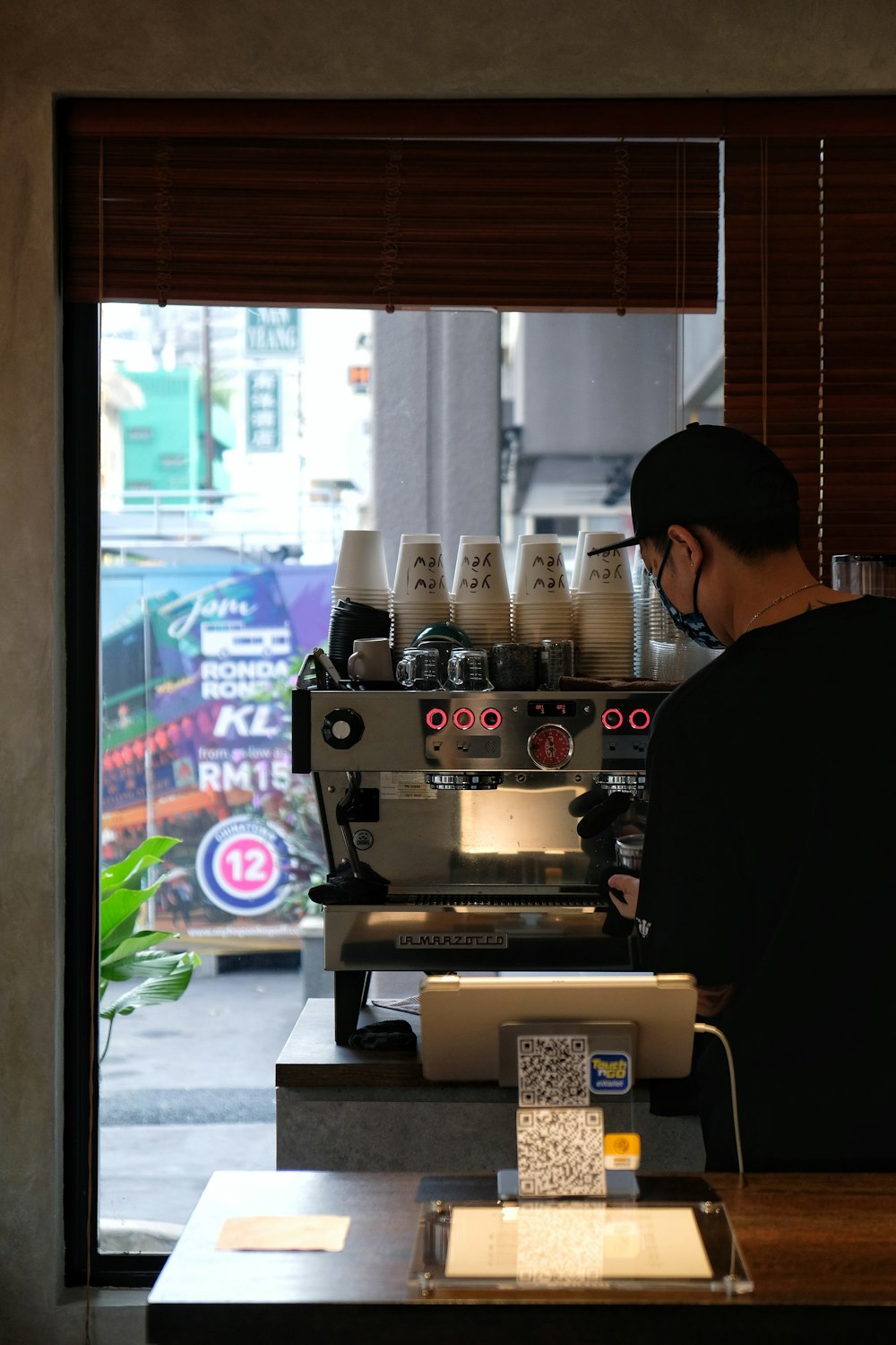 man in black shirt standing in front of espresso machine