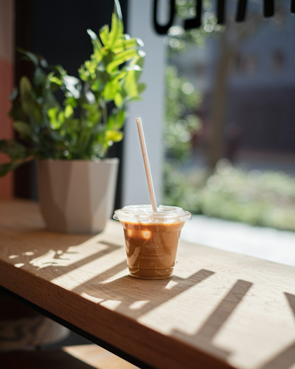 clear plastic cup with brown liquid on brown wooden table