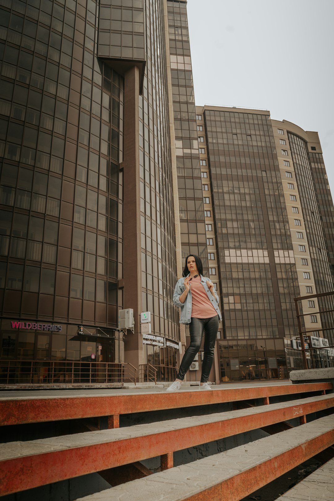 woman in white long sleeve shirt and blue denim jeans standing on brown wooden bridge