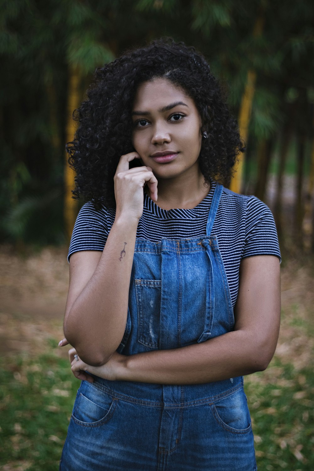 Mujer con camisa de rayas blancas y negras y peto de mezclilla azul