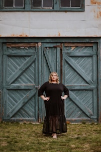woman in black long sleeve dress standing beside brown wooden door
