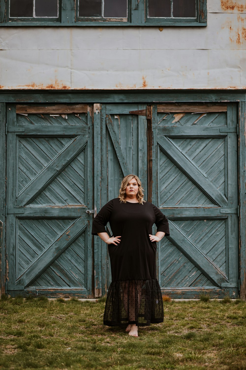 woman in black long sleeve dress standing beside brown wooden door