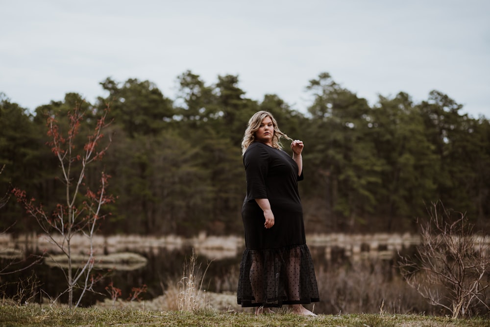 woman in black long sleeve dress standing on grass field during daytime