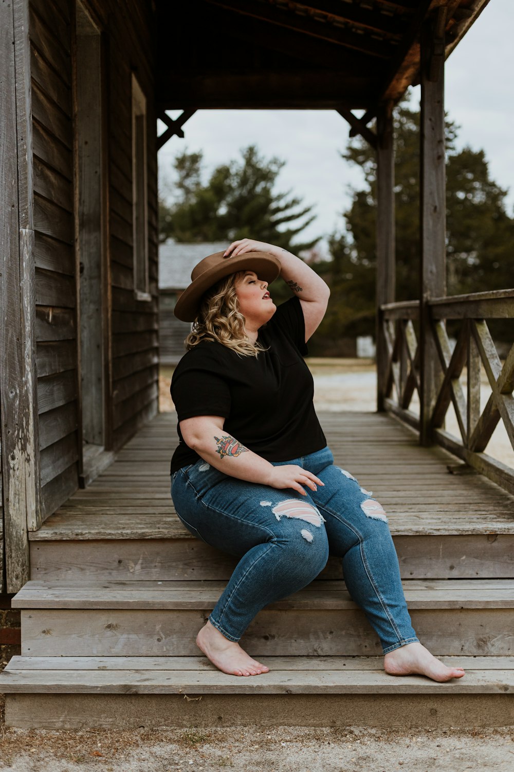 woman in black t-shirt and blue denim jeans sitting on wooden bridge photo  – Free Body positive Image on Unsplash