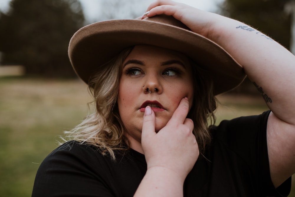 woman in black shirt wearing brown fedora hat