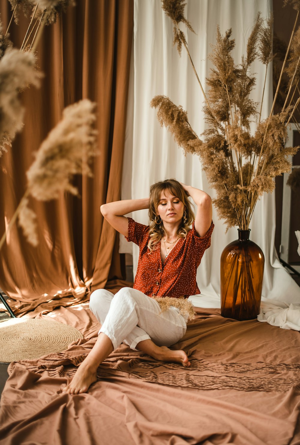 woman in brown long sleeve shirt and white pants sitting on bed