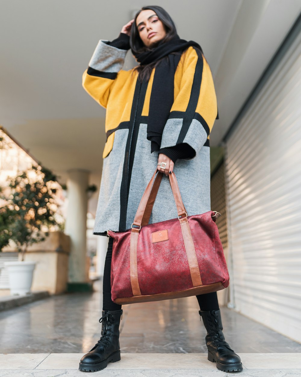 person in yellow black and white jacket carrying red leather sling bag