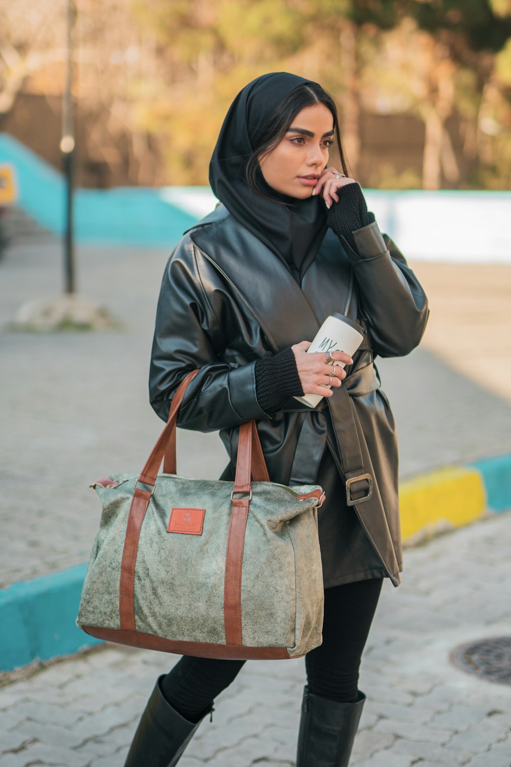 woman in black coat holding gray and brown handbag