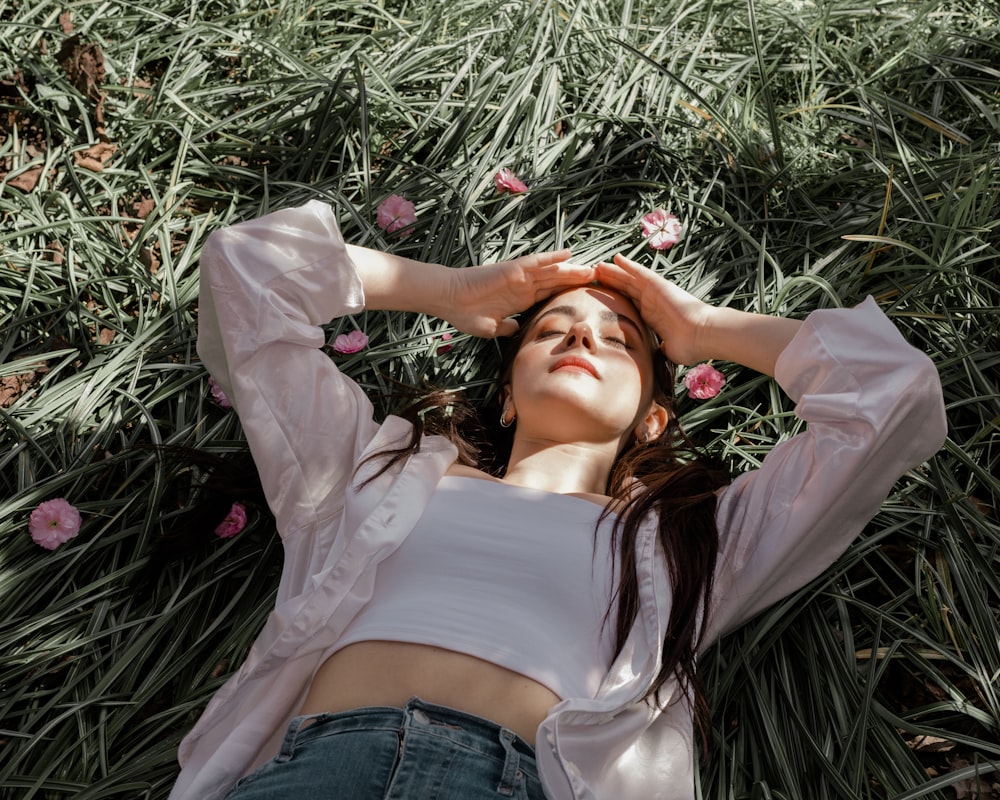 woman in white long sleeve shirt lying on green grass