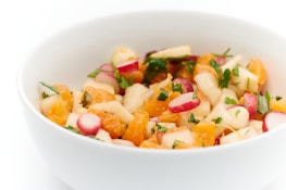 A colorful bowl of fresh salad with vibrant vegetables and herbs.