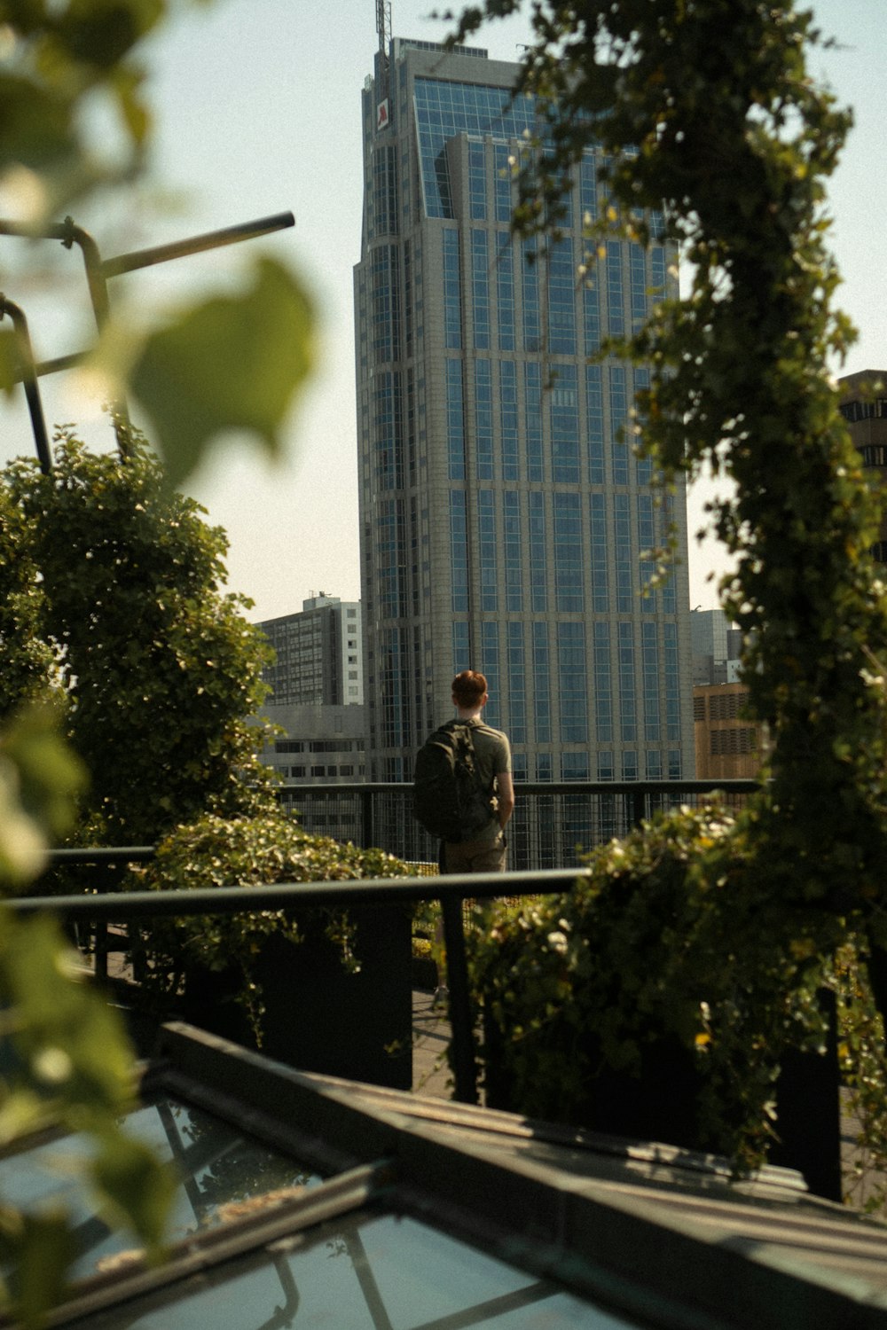 uomo in giacca grigia in piedi sul balcone durante il giorno