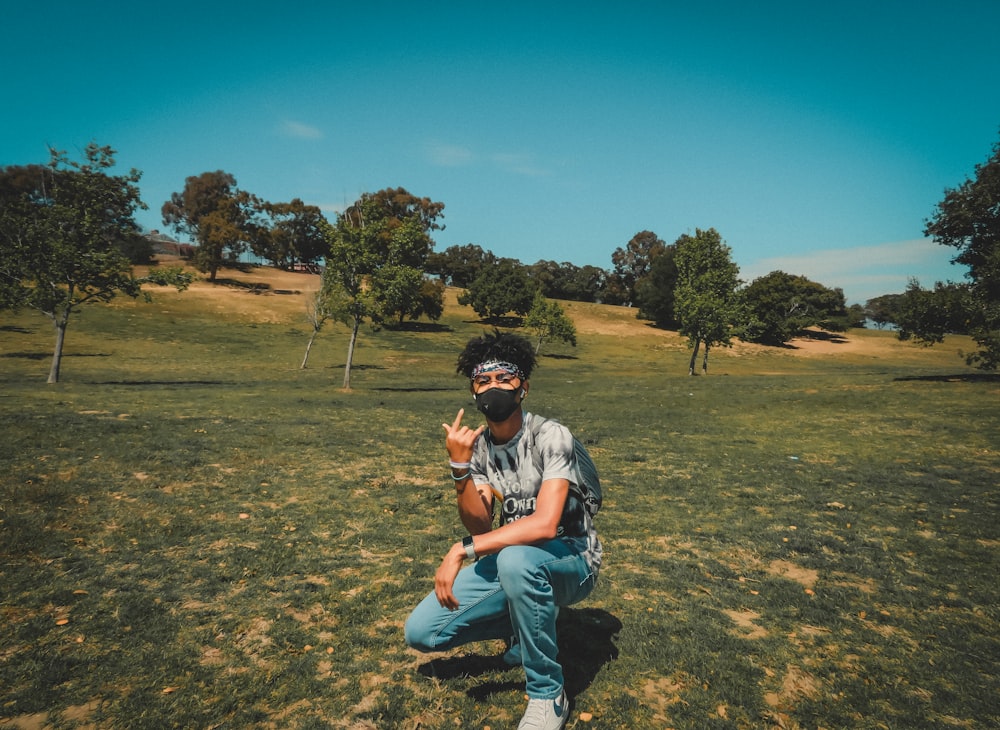 man in blue denim jeans sitting on green grass field during daytime