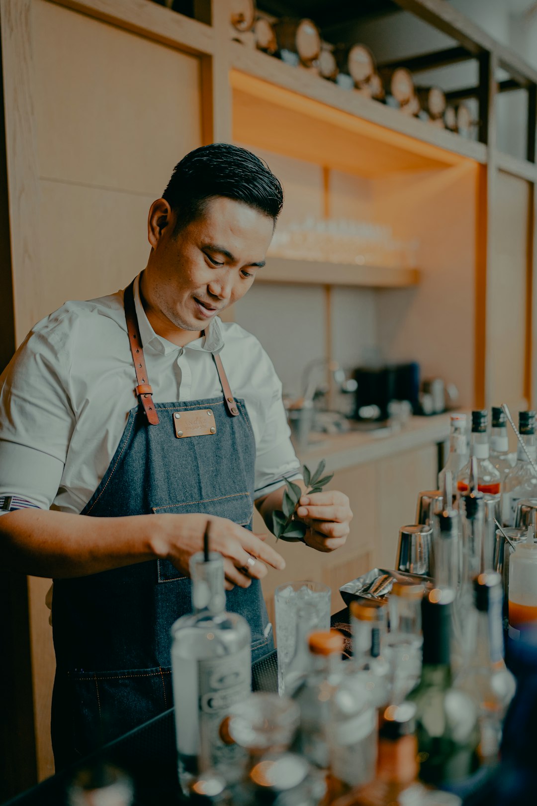 woman in white apron holding clear glass bottle