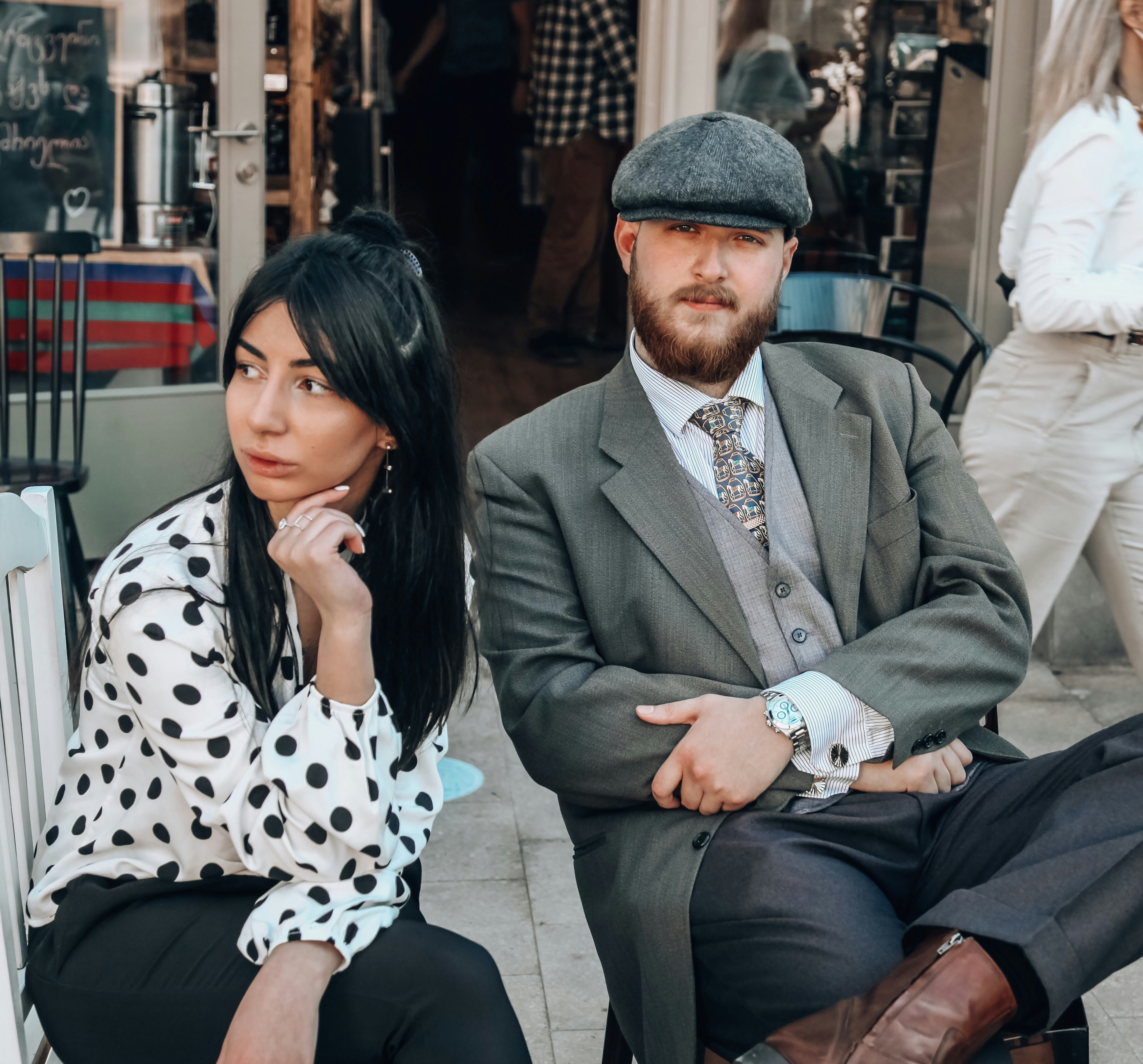 man in gray suit jacket sitting beside woman in black and white polka dot dress