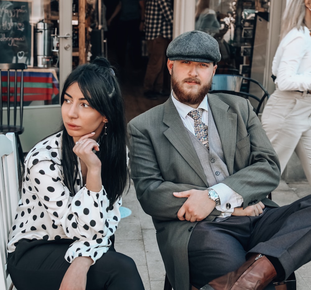 man in gray suit jacket sitting beside woman in black and white polka dot dress