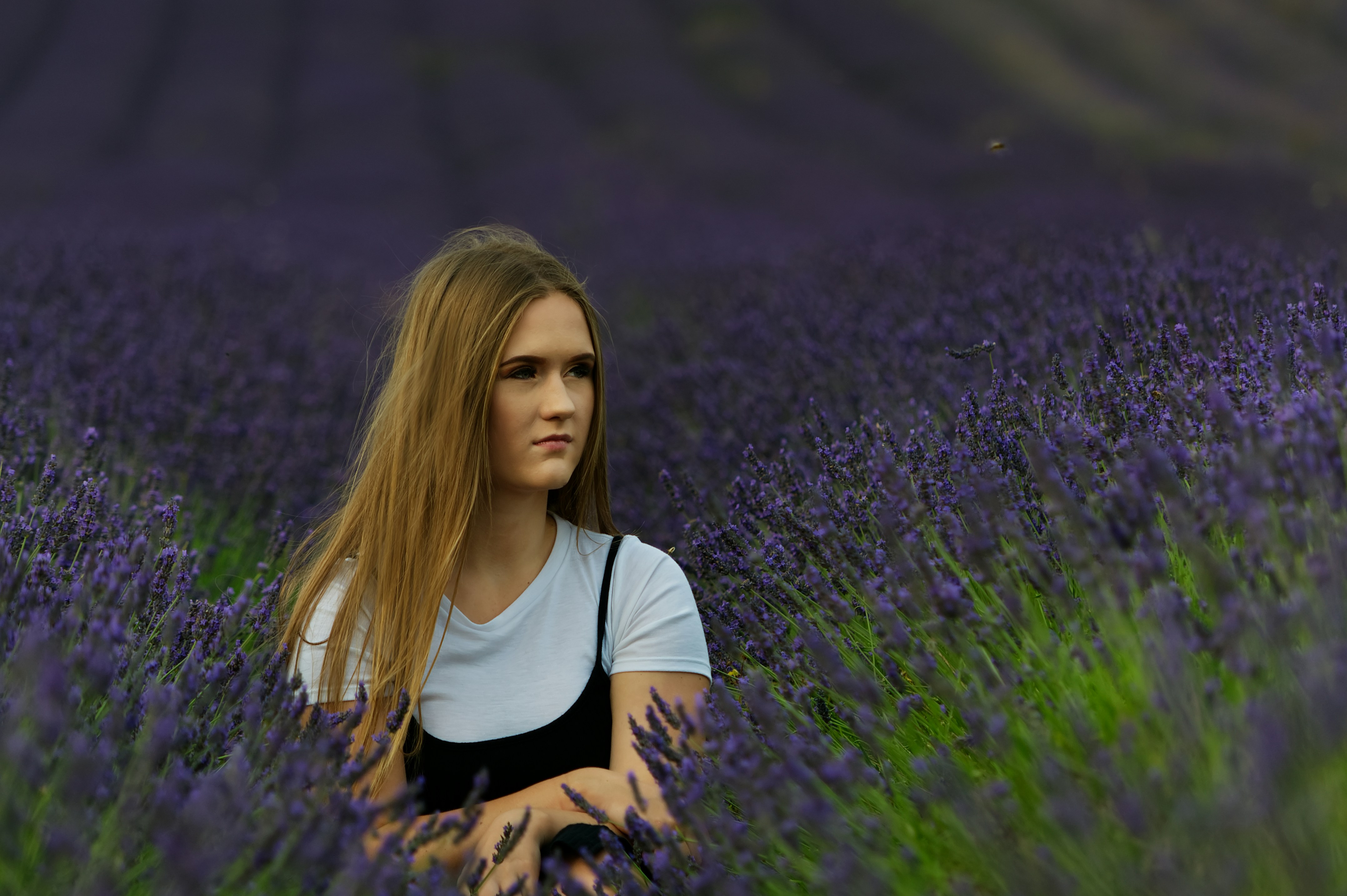 Woman in white and black t-shirt standing on purple flower field during daytime