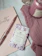 A cozy flat lay of blush pink beauty products and a softly lit journal on a cream fabric background.