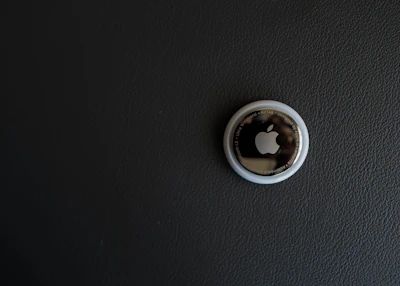 A close-up of a small, sleek smart tag device resting on a blue fabric background.