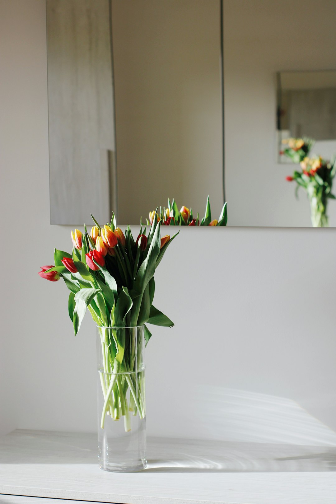 red and yellow flowers in clear glass vase